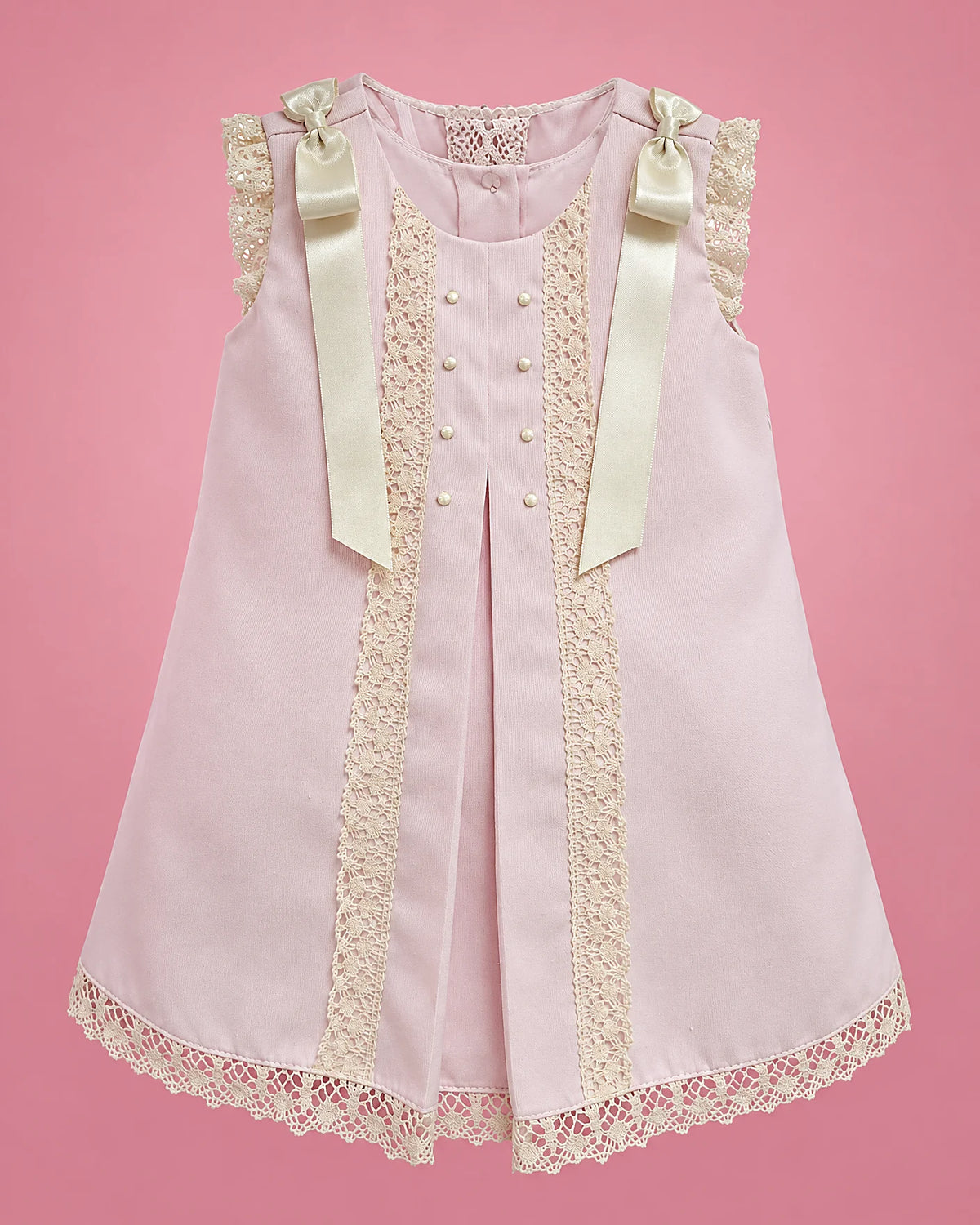 Vestido rosado con encaje crema, perlitas y lazos de cinta para bebé niña, vista de frente | JR Baby Center